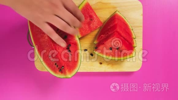 俯视图，女手用刀在木板上切水果，红色西瓜.. 天然健康食品的概念..