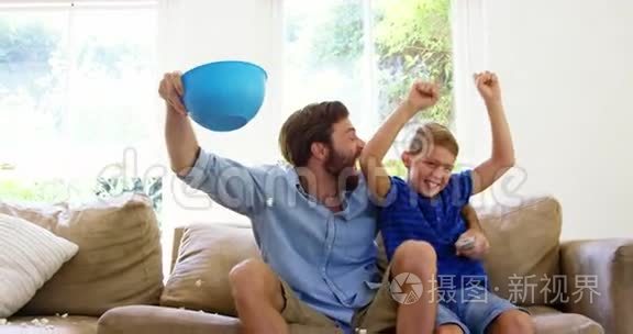 快乐的父亲和儿子在电视前享受视频