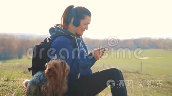 中年妇女和狗约克郡的游客带着背包在耳机里听音乐看着