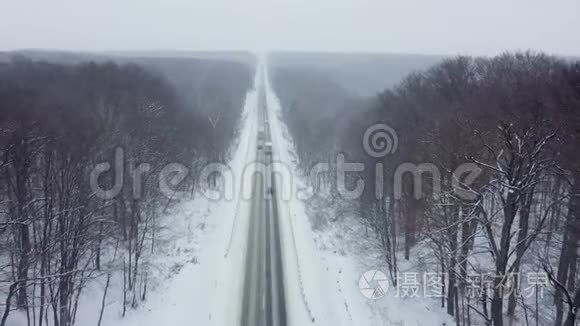 降雪时被冬季森林包围的道路上的交通鸟瞰图