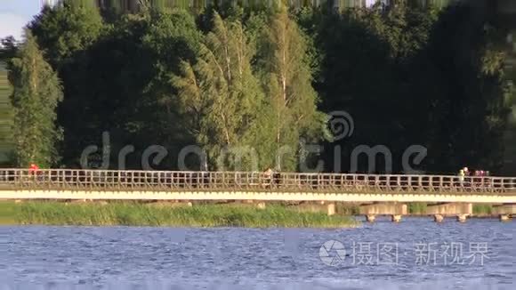 人们走在湖边的长长的木桥上视频