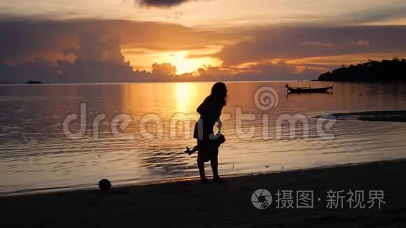 日落时分，带着孩子的女孩在海滩上散步和玩耍