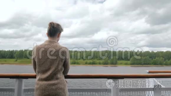 年轻女子站在游轮甲板上，看着河流和风景
