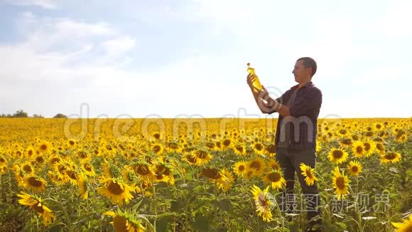 日落时分，农夫手捧一瓶葵花籽油. 慢动作视频。 农民农业塑料