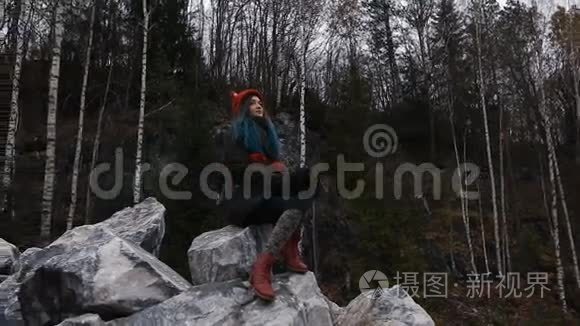艺术家女孩画坐在悬崖的岩石上，记事本。 奇妙的瀑布景观