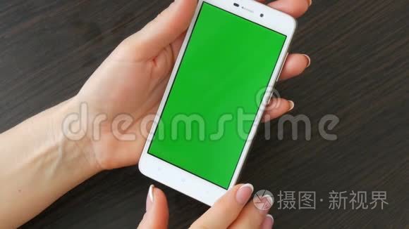 女性手与美丽的法国美甲采取白色智能手机与绿色屏幕。 使用智能手机，手持