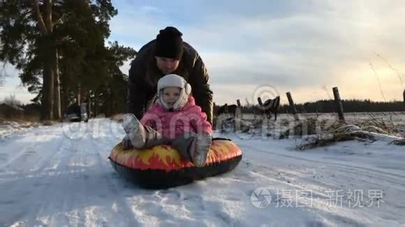 爸爸把女儿推到橡皮充气雪管上视频