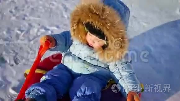 一个快乐的孩子骑在雪管上的雪山上