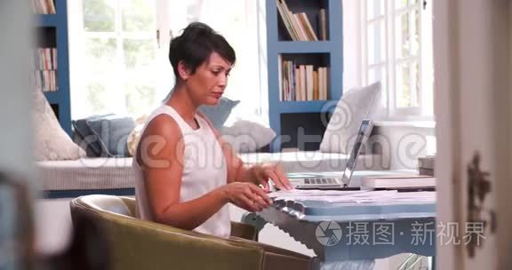 在家庭办公室工作的成熟妇女，带手提电脑