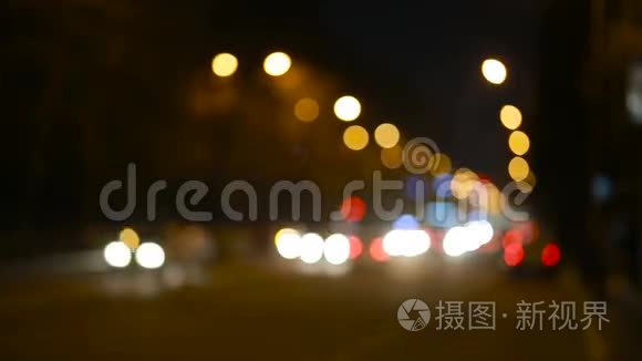 城市在夜间背景与汽车。 重点之外