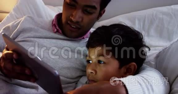 父子俩在床上用数码平板电脑