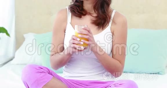 快乐的女人在床上喝橙汁视频