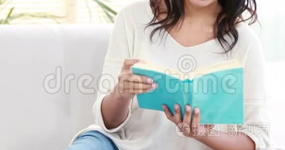 微笑的女人在沙发上看书