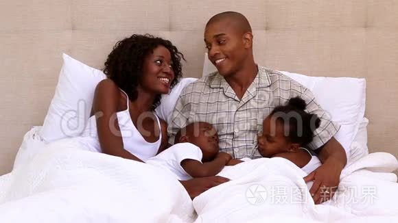 幸福的年轻家庭在床上在一起