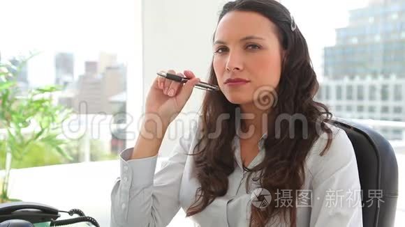 女商人一边拿着笔一边思考视频