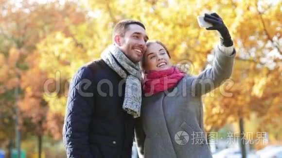 秋日公园有智能手机的微笑情侣