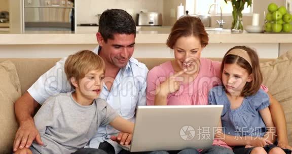 使用笔记本电脑坐在沙发上的幸福家庭