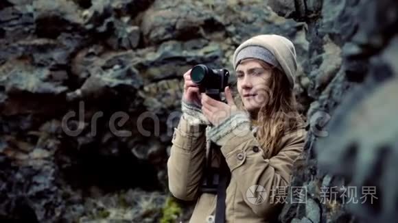 年轻漂亮的女人拿着相机在山上拍照。 旅行女性拍摄大自然。