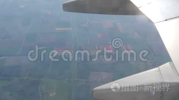 飞机飞过荷兰五彩郁金香美丽的田野，从舷窗俯瞰。 飞机机翼
