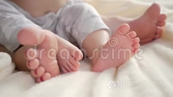 婴儿和他妈妈的腿在床上。 幸福的家庭观念。 美丽的产妇概念视频。