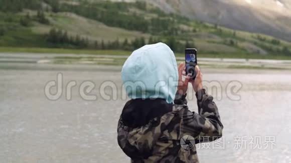 年轻的女人拿着手机坐在山里。 旅程