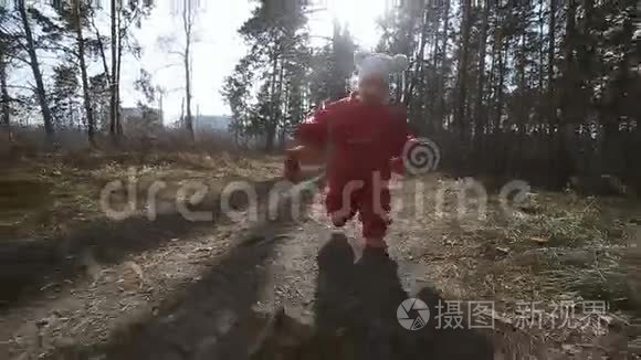 穿着红色工作服的小女孩穿过森林，微笑着看着镜头