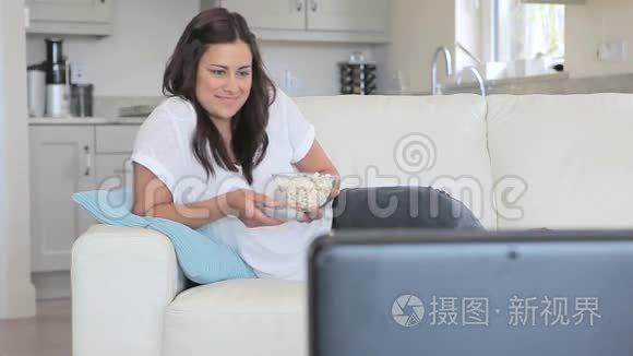 女人用爆米花看电视的视频