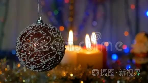 一个大红球。 新年和圣诞装饰品。 燃烧蜡烛。 闪耀的加兰。 背景模糊。