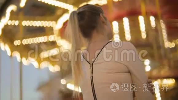 后景拍摄的优雅女人穿着衣服看着明亮的旋转木马在公园