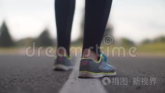 女跑步者的腿开始在路上奔跑。 穿跑鞋的女人腿特写