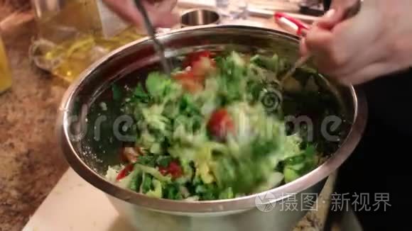 女性手在厨房里搅拌新鲜蔬菜沙拉和奶酪Feta。 蔬菜的混合。 特写