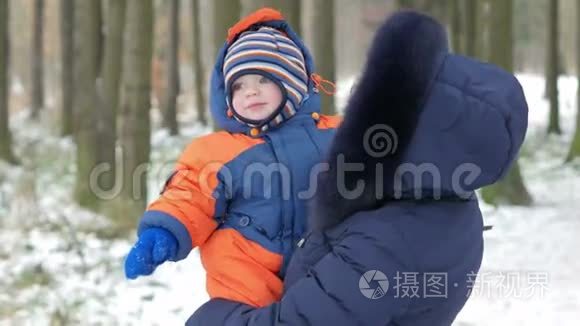 可爱的宝宝在冬天妈妈的怀里。 他们谈笑风生。 两人都穿着温暖的蓝色和橙色。 这就是