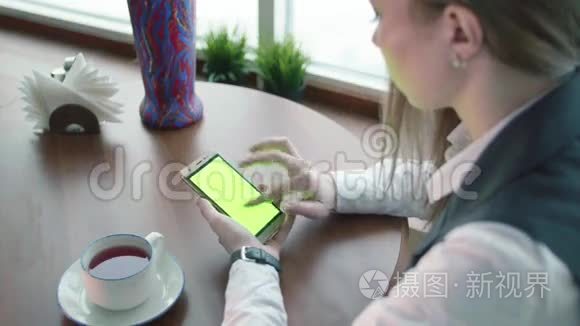 一位年轻的女巴士在咖啡馆工作，她用绿色的屏幕打电话