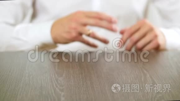 一个穿白色衬衫的人从手指上摘下订婚戒指。 关于离婚的决定。