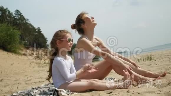 妈妈和女儿正在海滩上晒日光浴。 夏日晴天