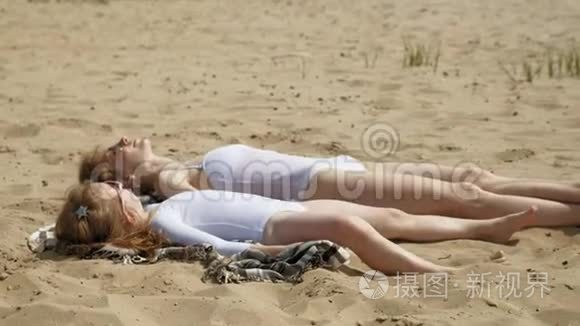 妈妈和女儿正在海滩上晒日光浴。 夏日晴天
