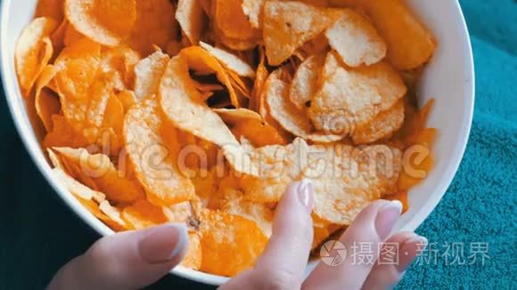 女人躺在蓝色毯子下面的沙发上,正在吃薯片短视频