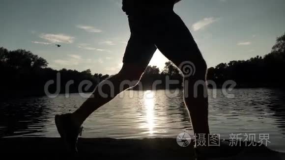 超级慢动作稳定夹男性跑步者日落剪影对水