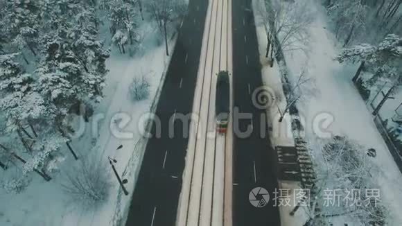 在冬季森林道路上的顶部可以看到汽车和电车。 雪花空中无人机镜头