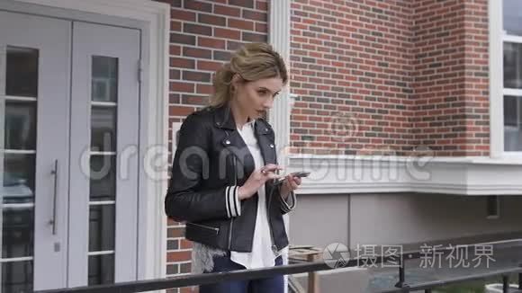 城市生活方式时尚的女孩使用手机短信智能手机应用程序在街道上。 金发女郎