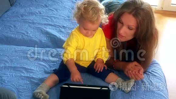 女人和她的小女儿在床上玩平板电脑