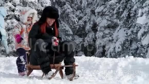 母亲和女儿在冬天打雪橇