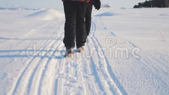 团队合作。 男游客摄影师在冬天乘三脚架爬山顶山顶岩峰群去雪