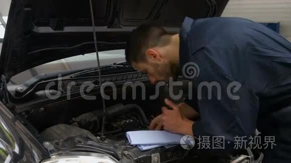 英俊的机械师检查汽车发动机里的油