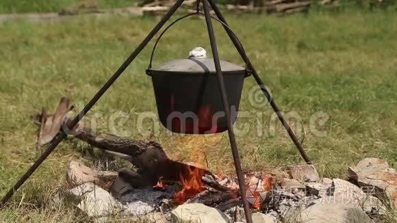 三脚架上的大锅在篝火上加热视频