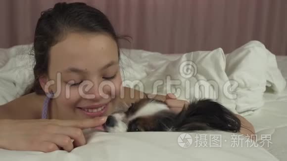 快乐少女亲吻和玩狗帕皮隆在床上股票视频