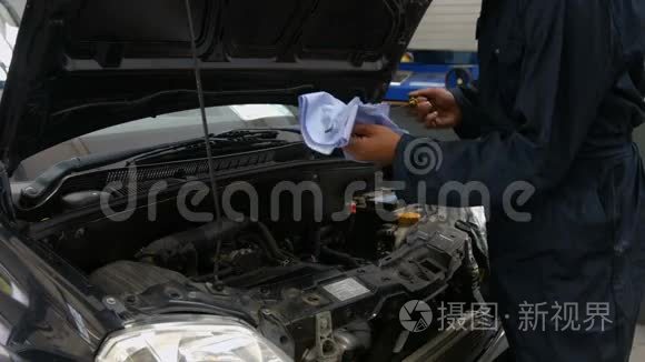 英俊的机械师检查汽车发动机里的油