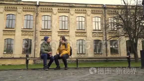 两个学生坐在校园附近的长凳上视频