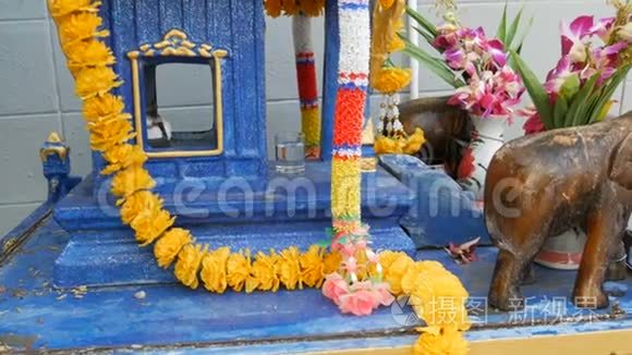 泰国花园中装饰精美的传统佛教祭坛，有鲜花和各种象征人物