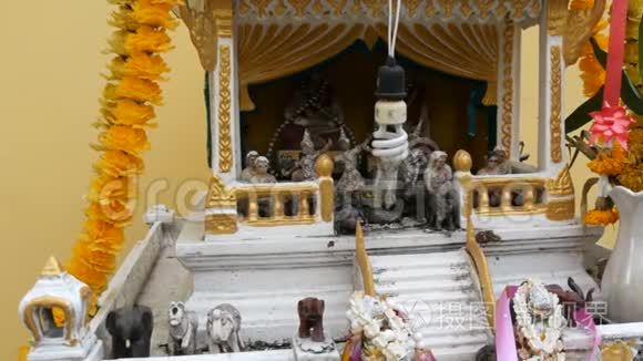 泰国花园中装饰精美的传统佛教祭坛，有鲜花和各种象征人物